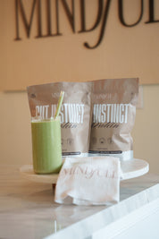 Two protein powder packets and a green smoothie on a white surface with 'MINDFULL' in the background.