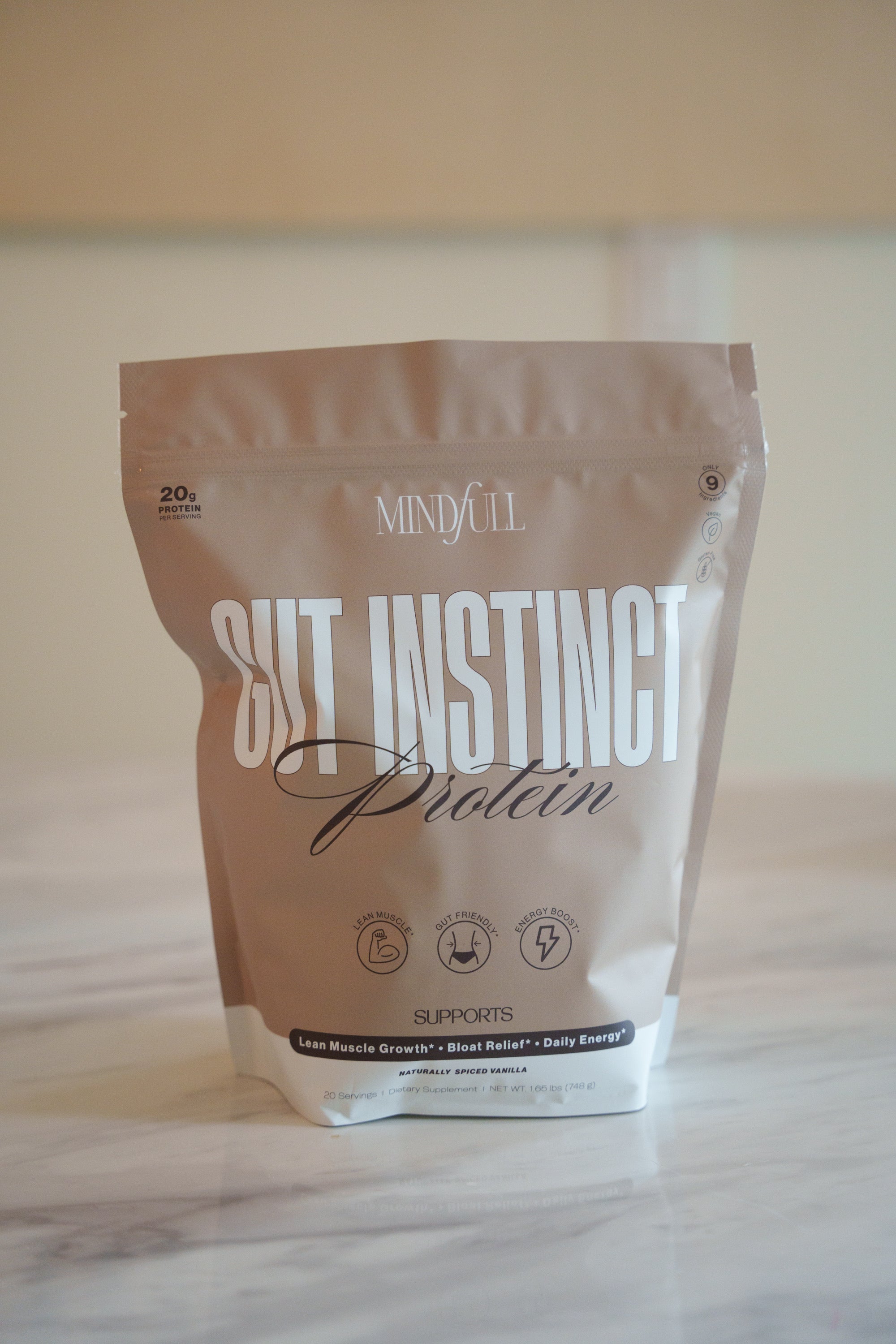 Protein powder package labeled 'GUT INSTINCT Protein' on a light surface with a neutral background
