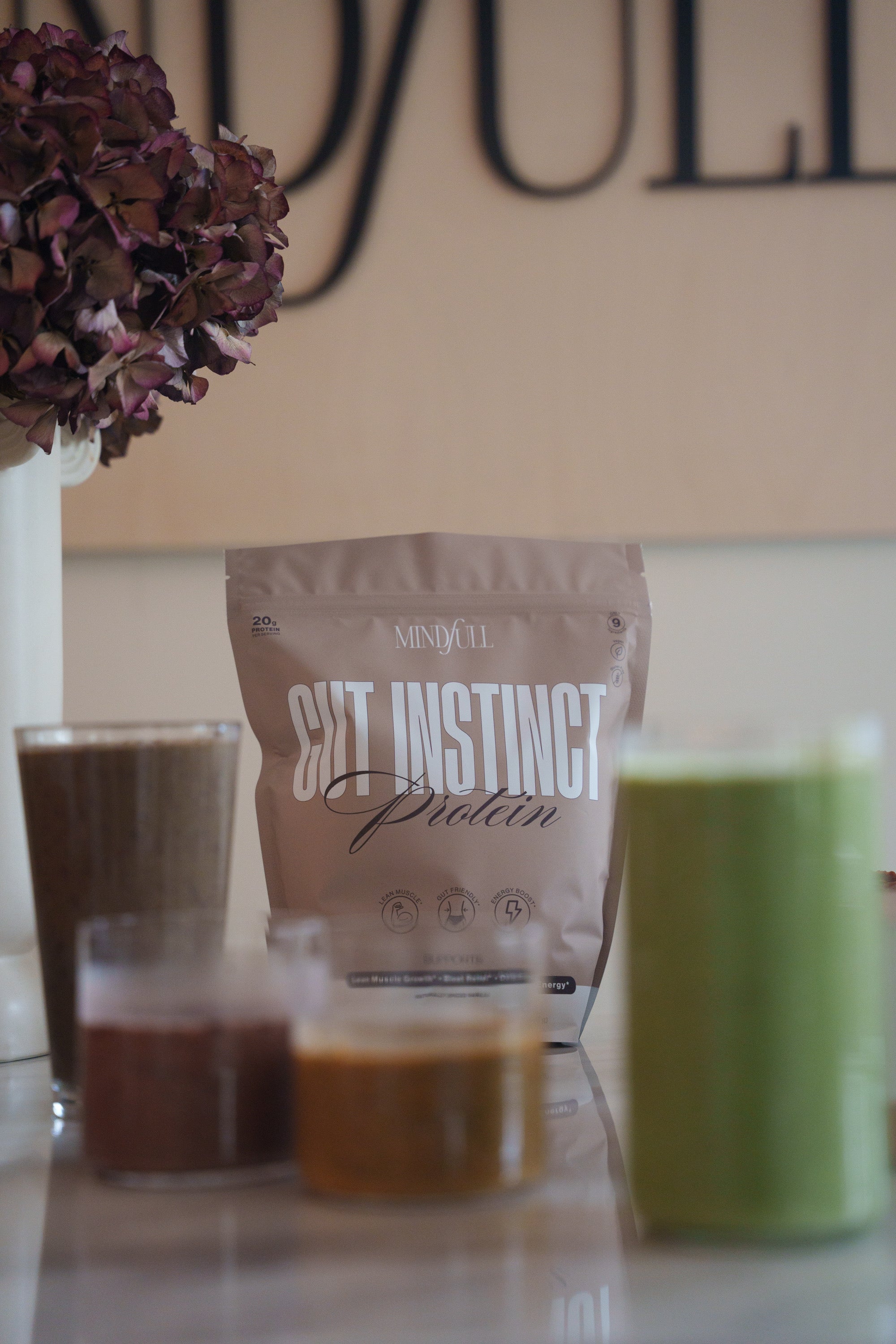 Protein powder package with various smoothies on a surface
